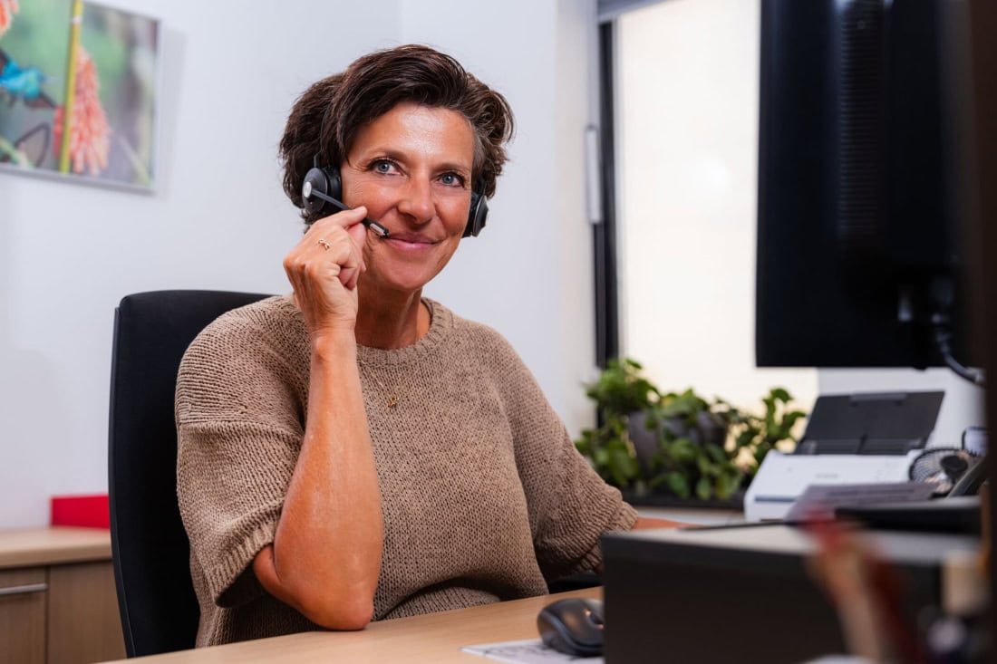 Healthcare professional with headset at call centre over GP and GP surgery.