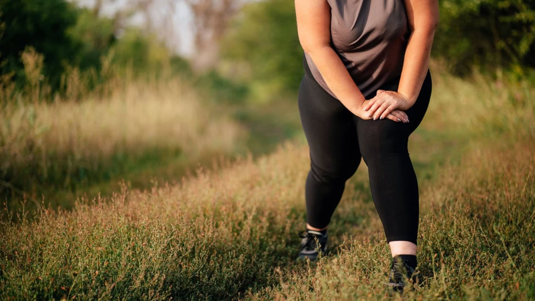 Overweight and exercise, woman in sports outfit in nature.