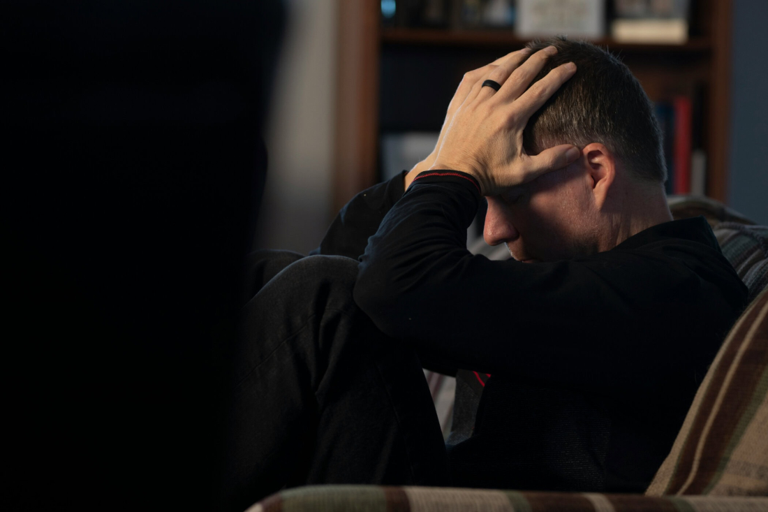 A man suffering from mental stress holds his head in a quiet room.